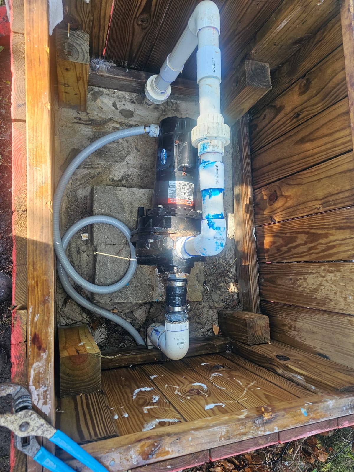 Well pump and PVC piping inside a wooden equipment enclosure